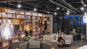 A modern library with bookshelves, comfortable seating, and a person reading. - Giappo Franca Kyoto (Kyoto)