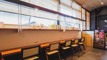 A modern interior with a long wooden bench, chairs, and a bookshelf with books and decorative items.