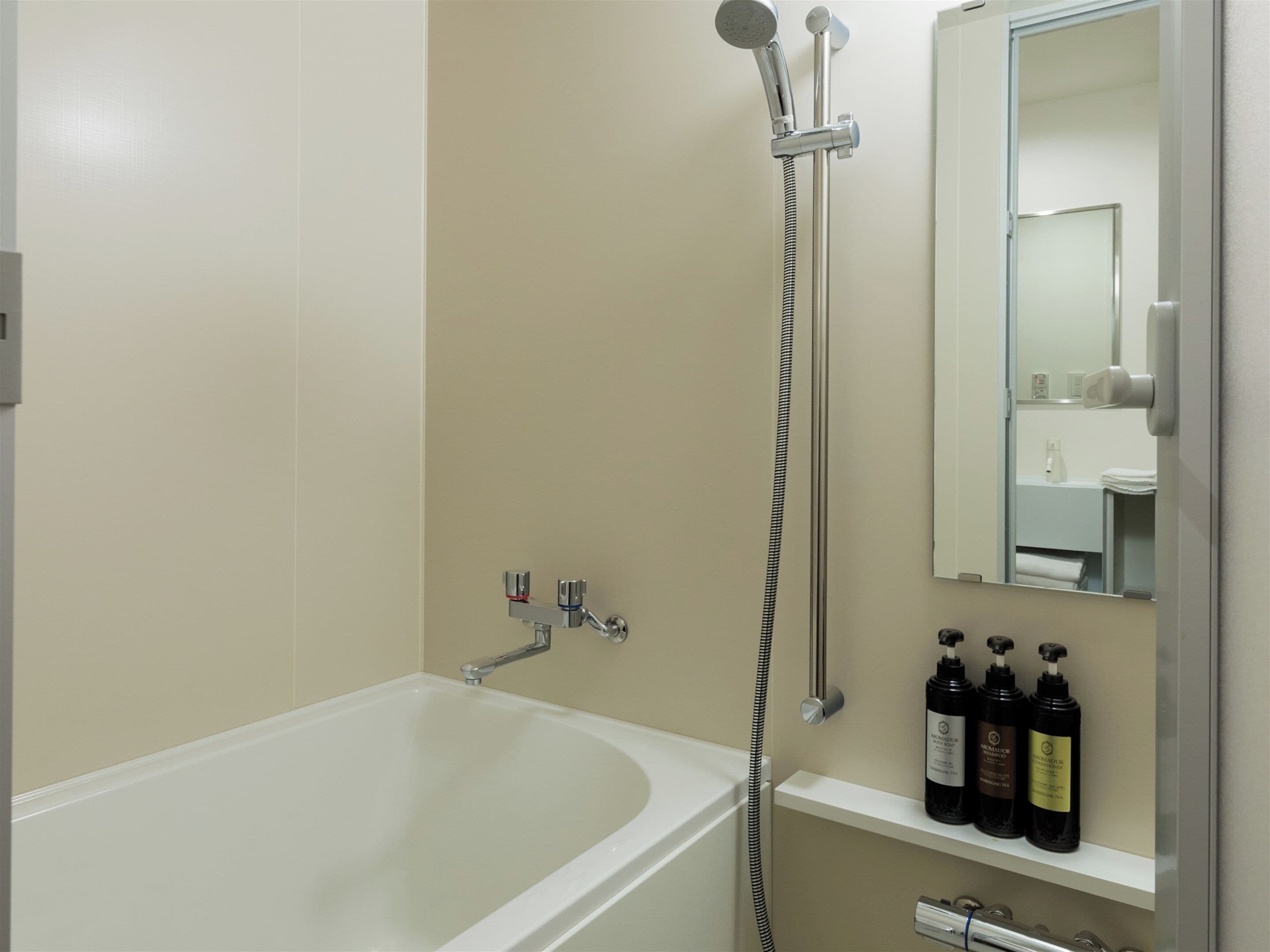 A bathroom with a bathtub, a shower, and a shelf with toiletries.