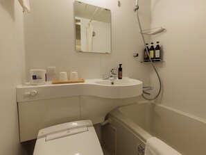 Une salle de bain avec un lavabo blanc, un miroir, une douche et des articles de toilette rangés sur une étagère.