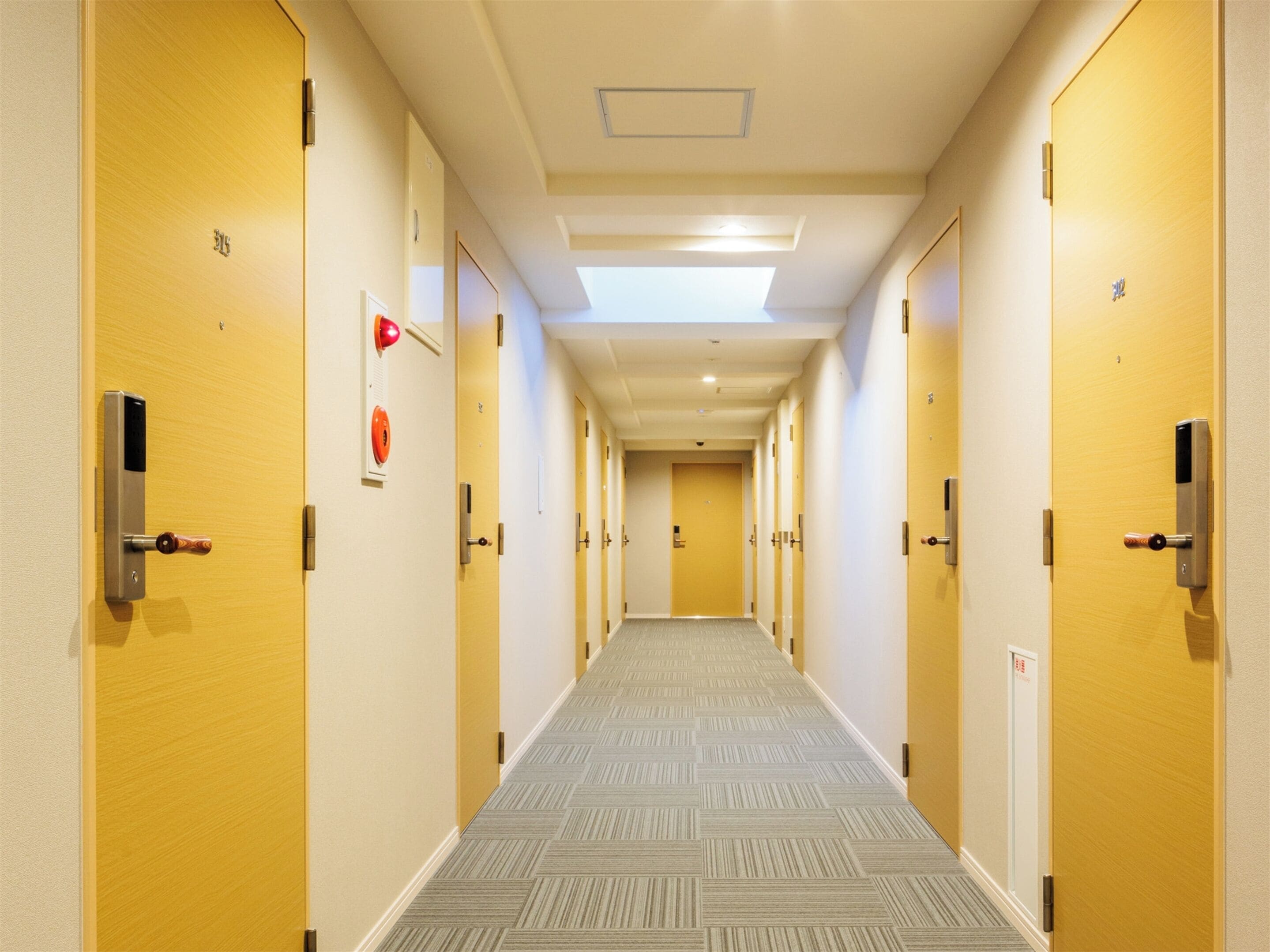 A hotel hallway with multiple doors, some with keypads and others with traditional locks.