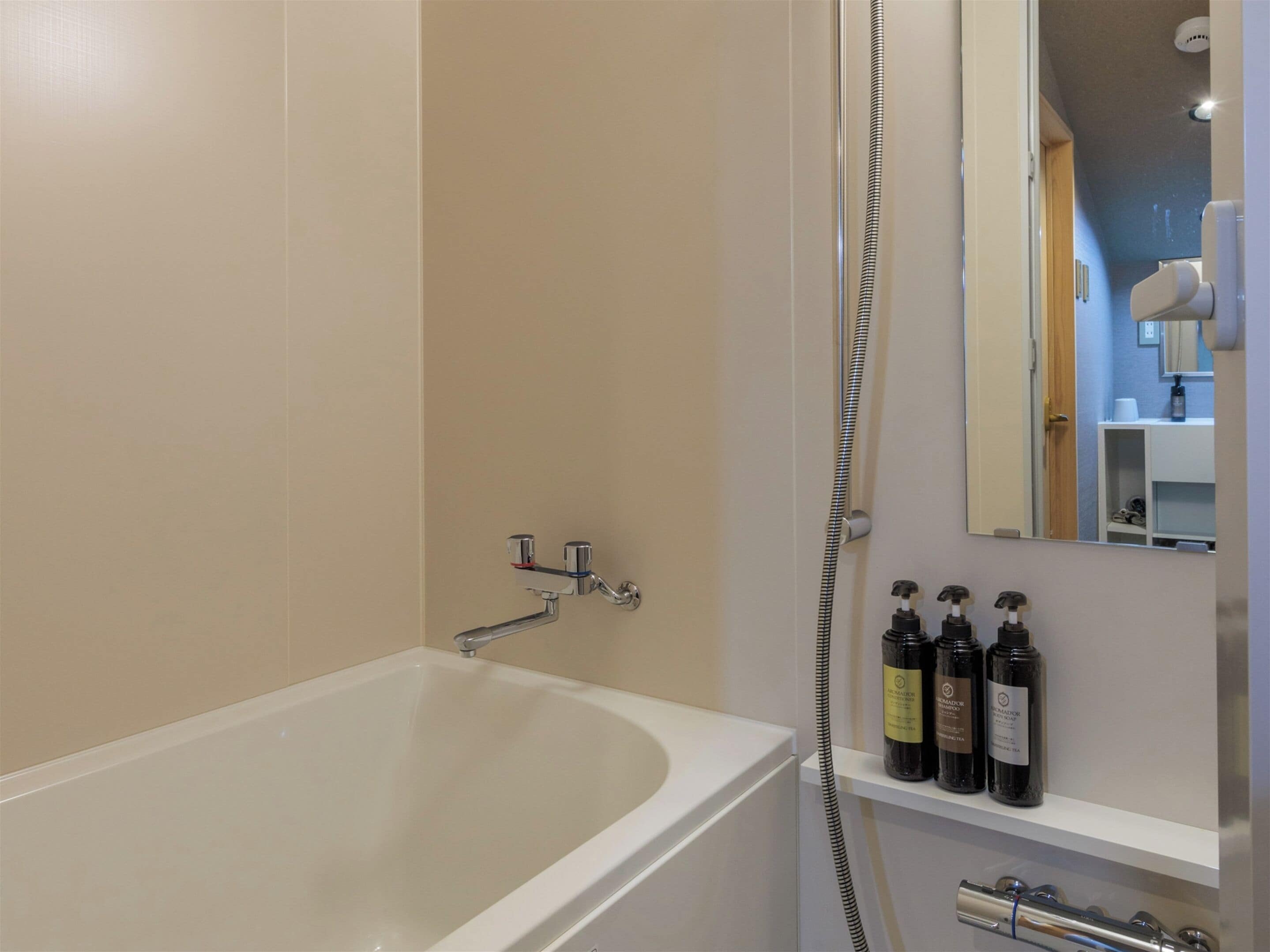 A modern bathroom with a bathtub, a shower, and a shelf with toiletries.