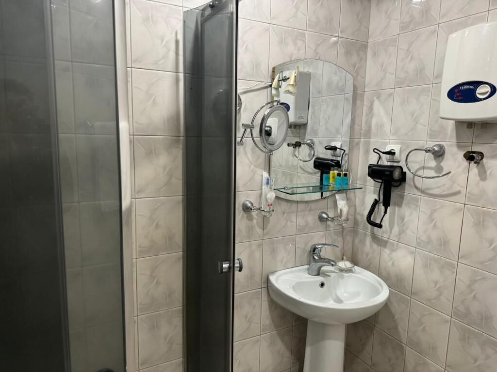 Un baño con cabina de ducha de vidrio, un lavabo blanco y un espejo.