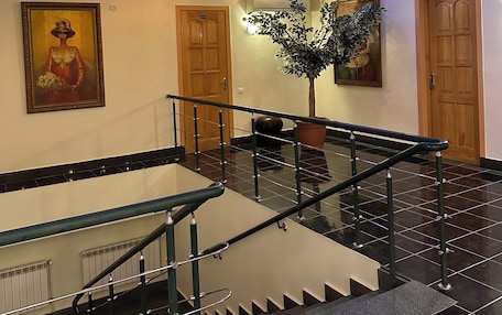 A modern hotel lobby with a staircase, a large painting, and a potted plant.
