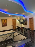 Un moderno vestíbulo de hotel con una escalera, un cuadro grande y una planta en maceta.