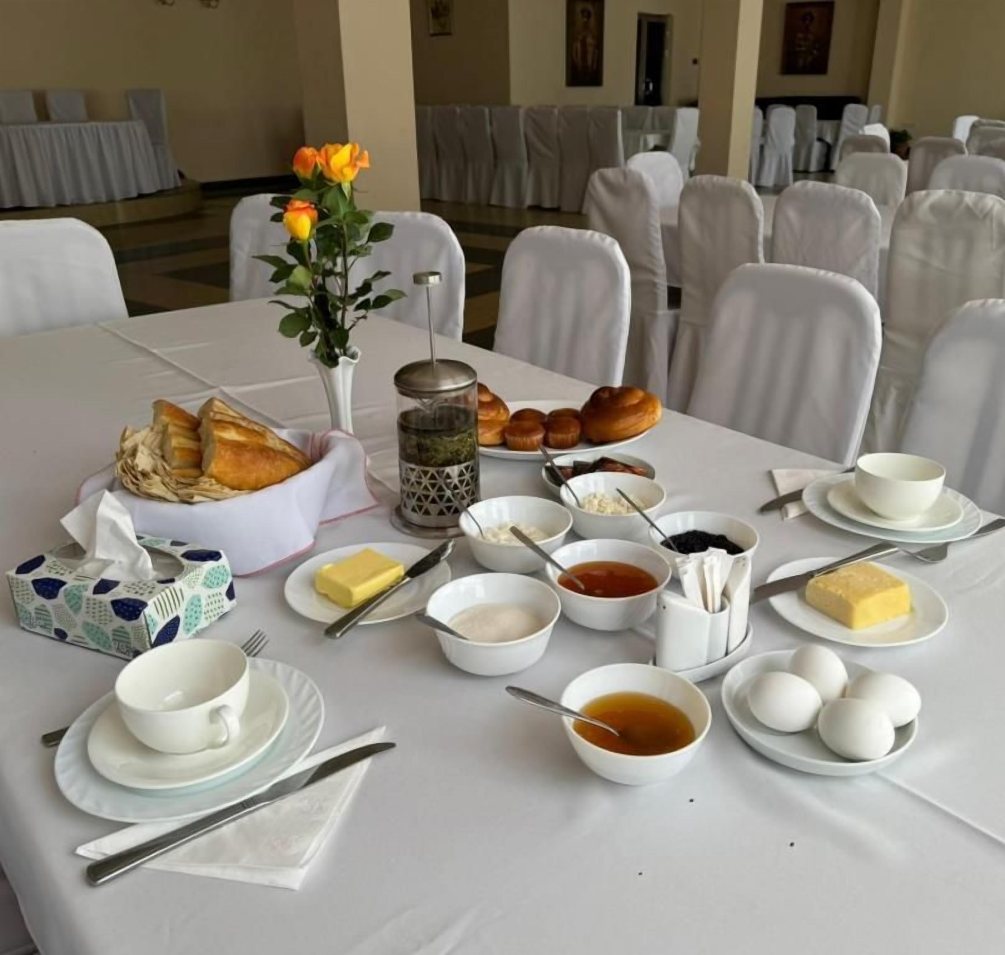 A breakfast table set with bread, eggs, butter, and various condiments.