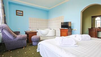 Una habitación de hotel con cama, una silla, una bañera, televisión y escritorio.