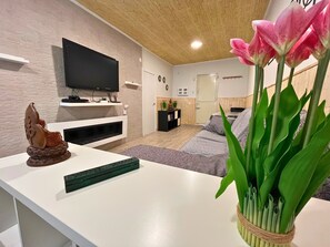 Una sala moderna con un televisor de pantalla plana, una estatua decorativa de Buda y una planta en maceta.
