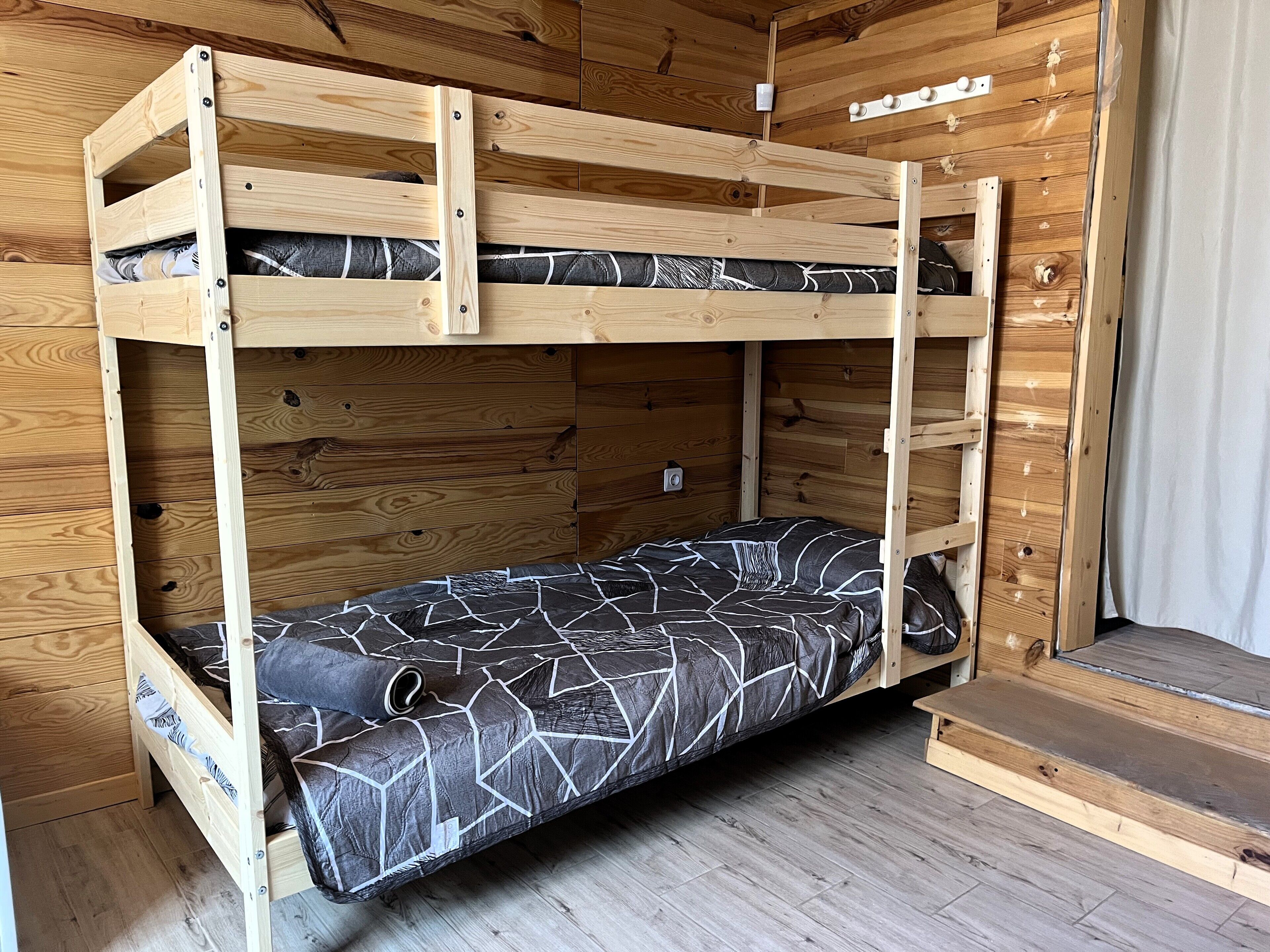 Een stapelbed met een onderbed en een matras met een geometrisch patroon.