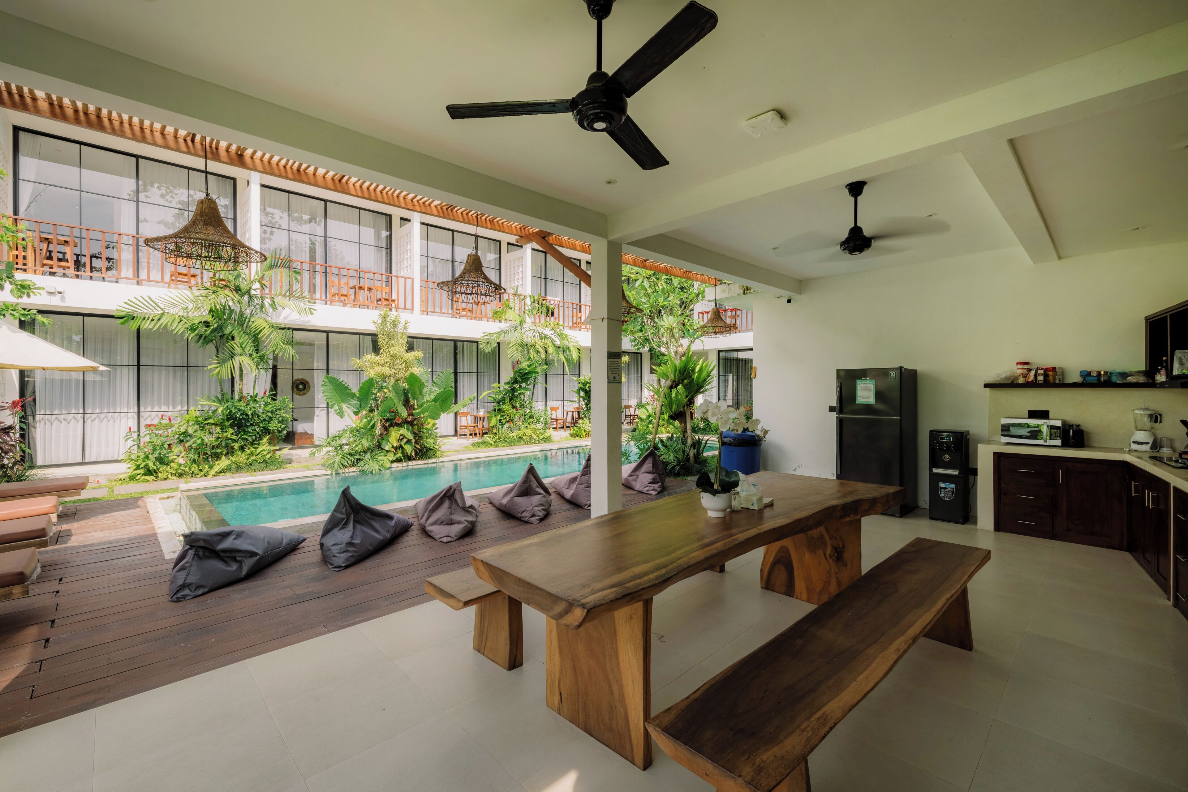 A spacious indoor area with a wooden table, a pool, and a balcony with plants.