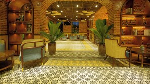 A lobby with brick walls, a patterned floor, and furniture including chairs and tables. - Boutik Cham Hotel Nha Trang  (Nam Nha Trang)