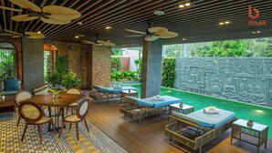 A covered outdoor area with wooden flooring, wicker furniture, and ceiling fans. - Boutik Cham Hotel Nha Trang  (Nam Nha Trang)