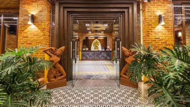 A hotel entrance with brick walls, a reception desk, and two statues on either side. - Boutik Cham Hotel Nha Trang  (Nam Nha Trang)