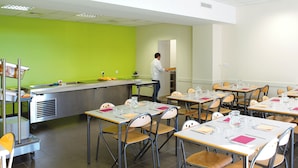 A classroom with tables and chairs, a teacher at the front, and a green wall. - jeune france accueil et formation  (Cholet)
