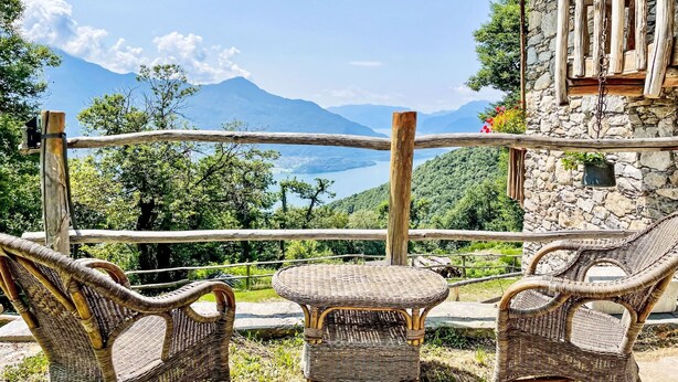 A rustic outdoor seating area with wicker furniture overlooking a mountainous landscape.