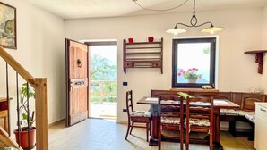 A dining area with wooden furniture, a window with a view, and a staircase leading to an outdoor area.