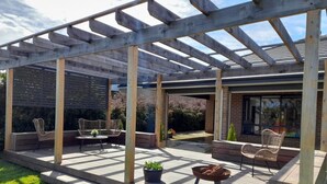 A covered patio area with wooden beams, outdoor furniture, and potted plants.