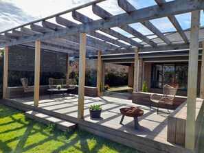 Ein überdachter Patio-Bereich mit Holzbalken, Gartenmöbeln und Topfpflanzen.