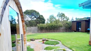 A backyard with a wooden deck, a gravel path, and a fenced area.