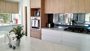 A modern kitchen with wooden cabinets, a built-in oven, a microwave, and a gas stove.