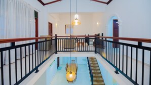 Ein geräumiger Innenraum mit hoher Decke, einer Treppe, die zu einer oberen Ebene führt, und einem Essbereich mit Tisch und Stühlen.