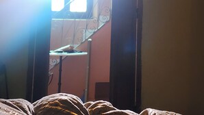 A bedroom with a bed, a window, and a staircase leading to an upper floor. - Local Moroccan Style House, Central Medina (Marrakech)