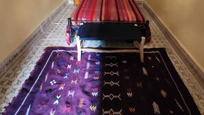Una habitación con una cama, un tapete estampado y un banco de madera.