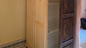 A wooden wardrobe with a mirrored door, a tiled floor, and a partially visible door frame. - Local Moroccan Style House, Central Medina (Marrakech)