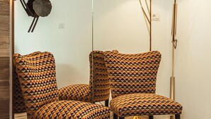 A room with two patterned armchairs, a floor lamp, and a wall-mounted decorative piece. - Da Riva Suite&Pool (Polignano a Mare)