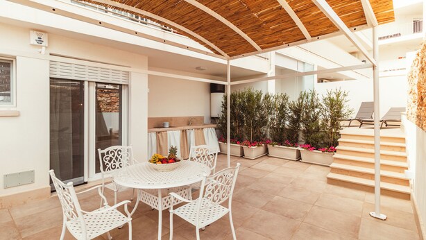 An outdoor patio with a round table and white chairs, a wooden ceiling, and potted plants. - Da Riva Suite&Pool (Polignano a Mare)
