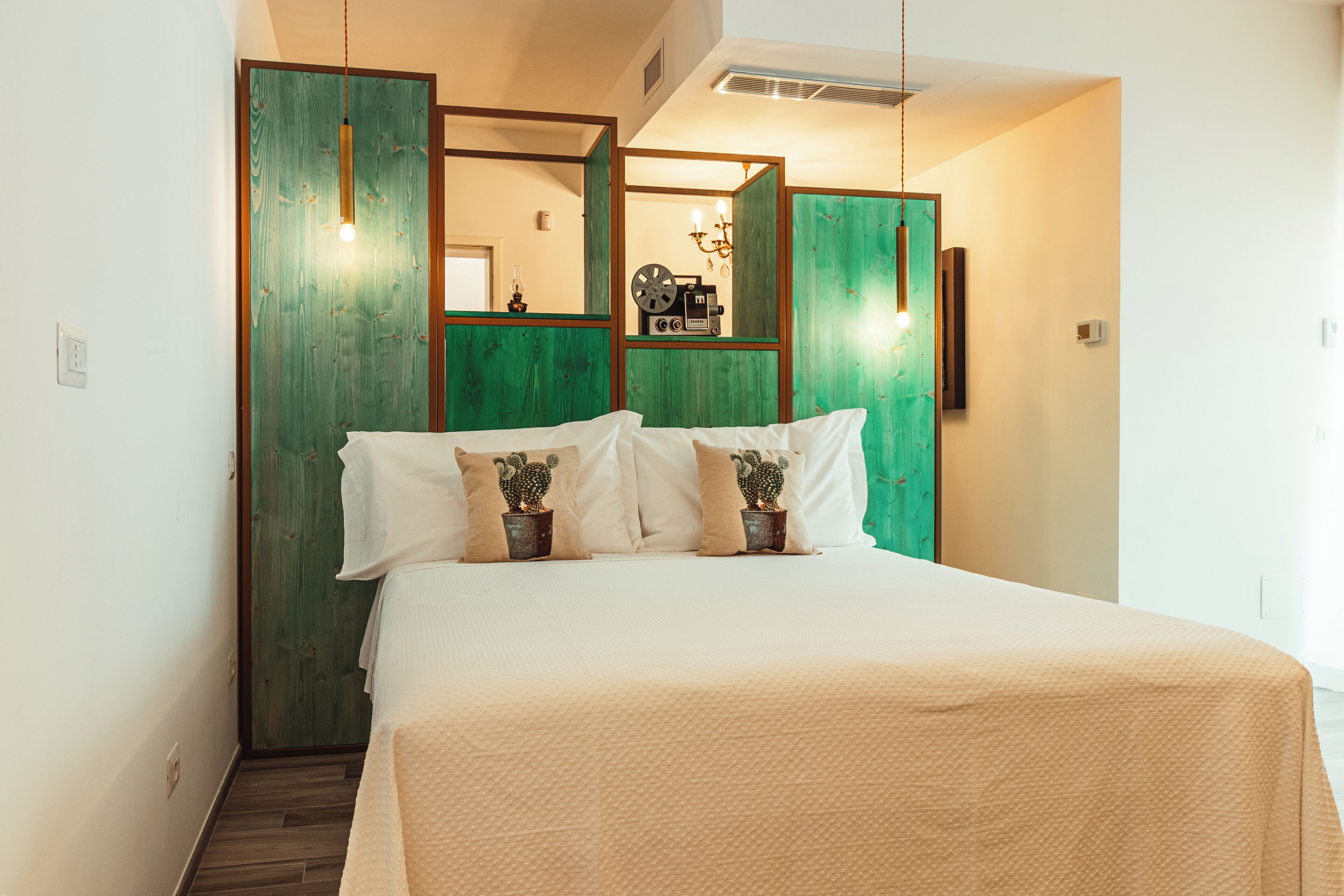 A bedroom with a bed, pillows, a mirror, and a green wardrobe.