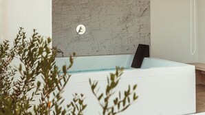 A modern bathroom with a marble wall, a bathtub, and a shower area. - Da Riva Suite&Pool (Polignano a Mare)