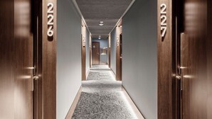 Een hotelhal met houten deuren genummerd 227, vloerbedekking en een modern plafondontwerp.