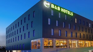 Een bed-and-breakfast hotel met een moderne gevel, grote ramen en een goed verlichte entree.