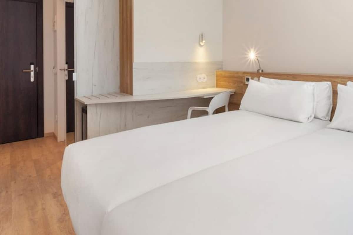 Ein Hotelzimmer mit einem großen Bett, einem Schreibtisch und einem Stuhl.