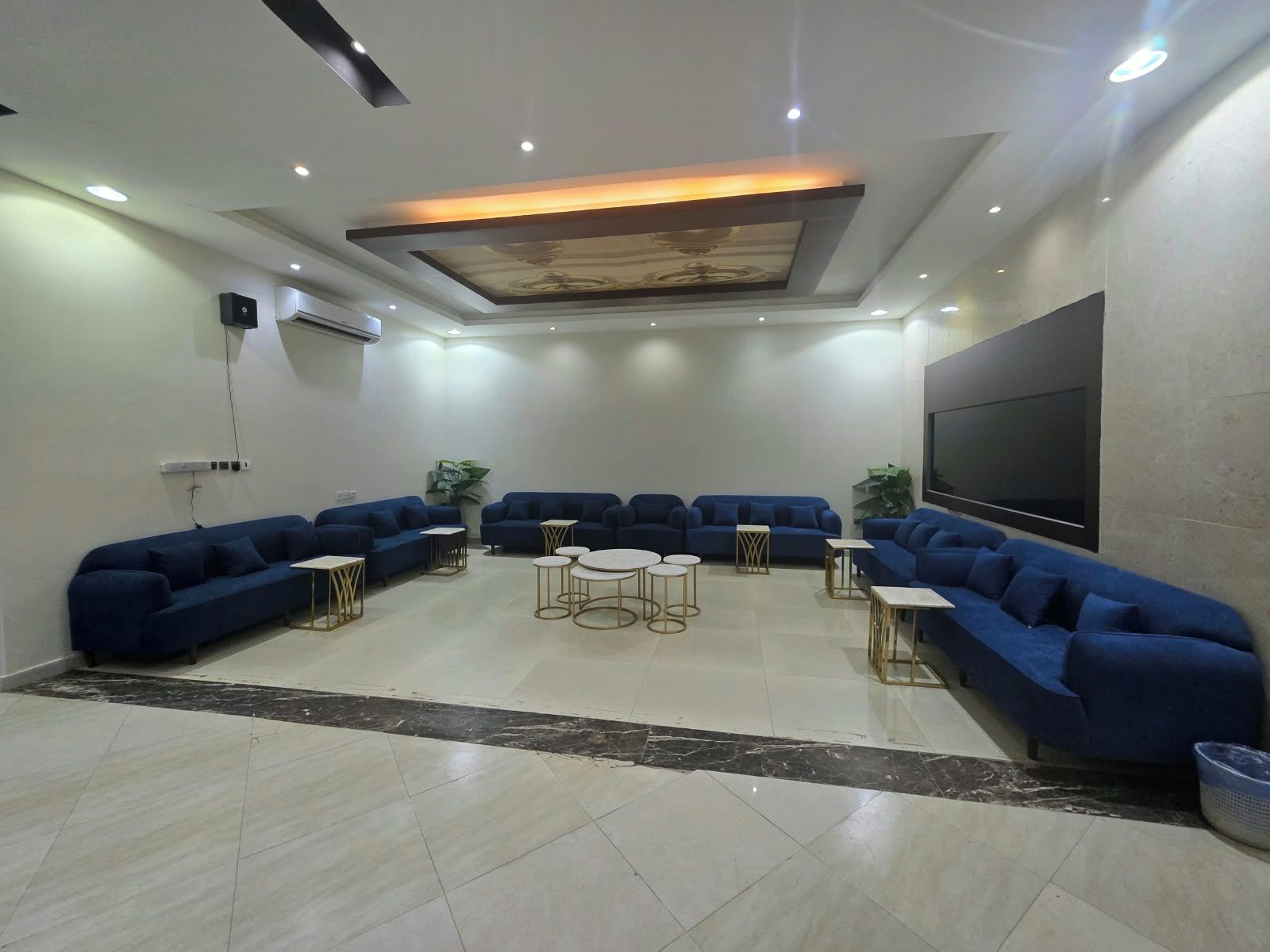 Un salon moderne avec un canapé d’angle, un téléviseur à écran plat et un plafond doté d’un éclairage encastré.