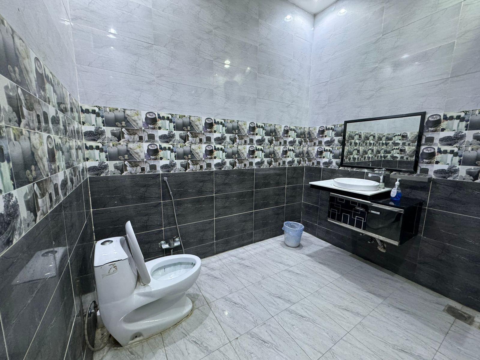 Egy modern fürőszoba, amelyben WC, mosdókagyló és tükör található.