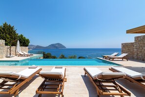 A poolside area with lounge chairs and a clear view of the sea.