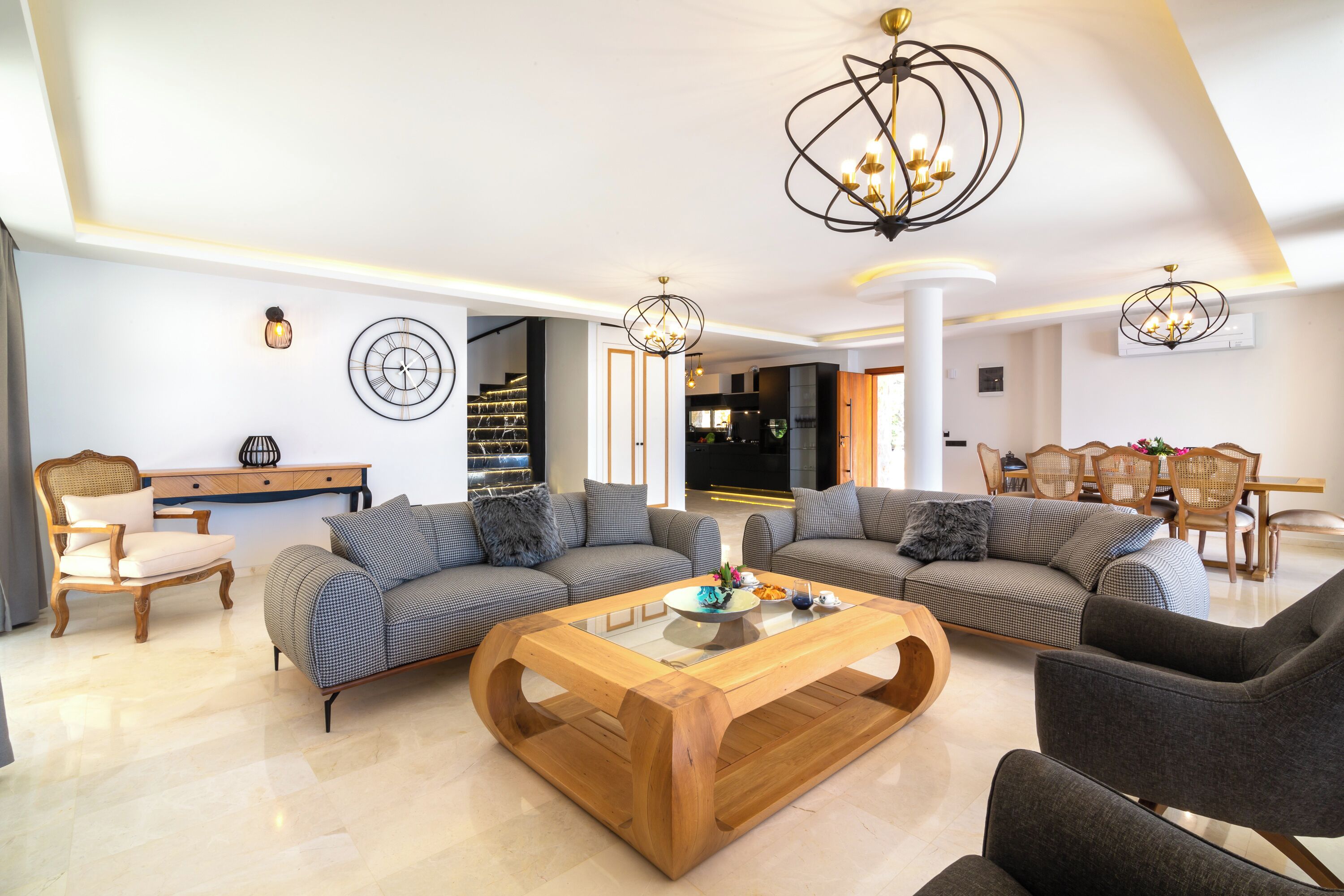 A modern living room with two sofas, a wooden coffee table, and a dining area with chairs.