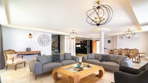 A modern living room with two sofas, a wooden coffee table, and a dining area with chairs.