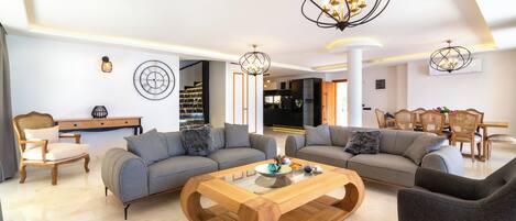 A modern living room with two sofas, a wooden coffee table, and a dining area with chairs.