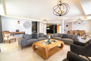 Uma sala de estar moderna com dois sofás, uma mesa de centro de madeira e uma área de jantar com cadeiras.