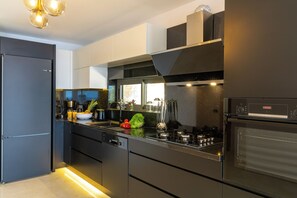 Una cocina moderna con refrigerador negro, electrodomésticos de acero inoxidable y horno empotrado.
