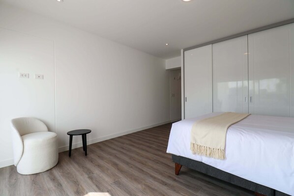 A modern bedroom with a bed, a chair, and a small table.
