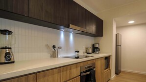 Eine moderne Küche mit Holzausbau, einem eingebauten Backofen, einem Edelstahlkühlschrank und einer Arbeitsplatte mit einem Mixer.