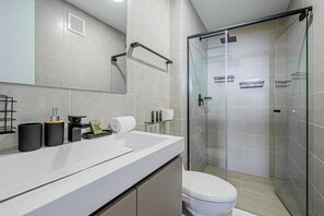 A modern bathroom with a glass shower enclosure, a white sink, and a toilet. - w* | Minimalist 1BR w/ Balcony in San Francisco (Panamá)