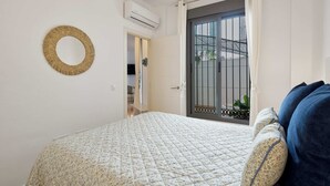 Ein Schlafzimmer mit einem Bett, einem runden Spiegel und Blick durch eine Tür mit einem Metallgitter.