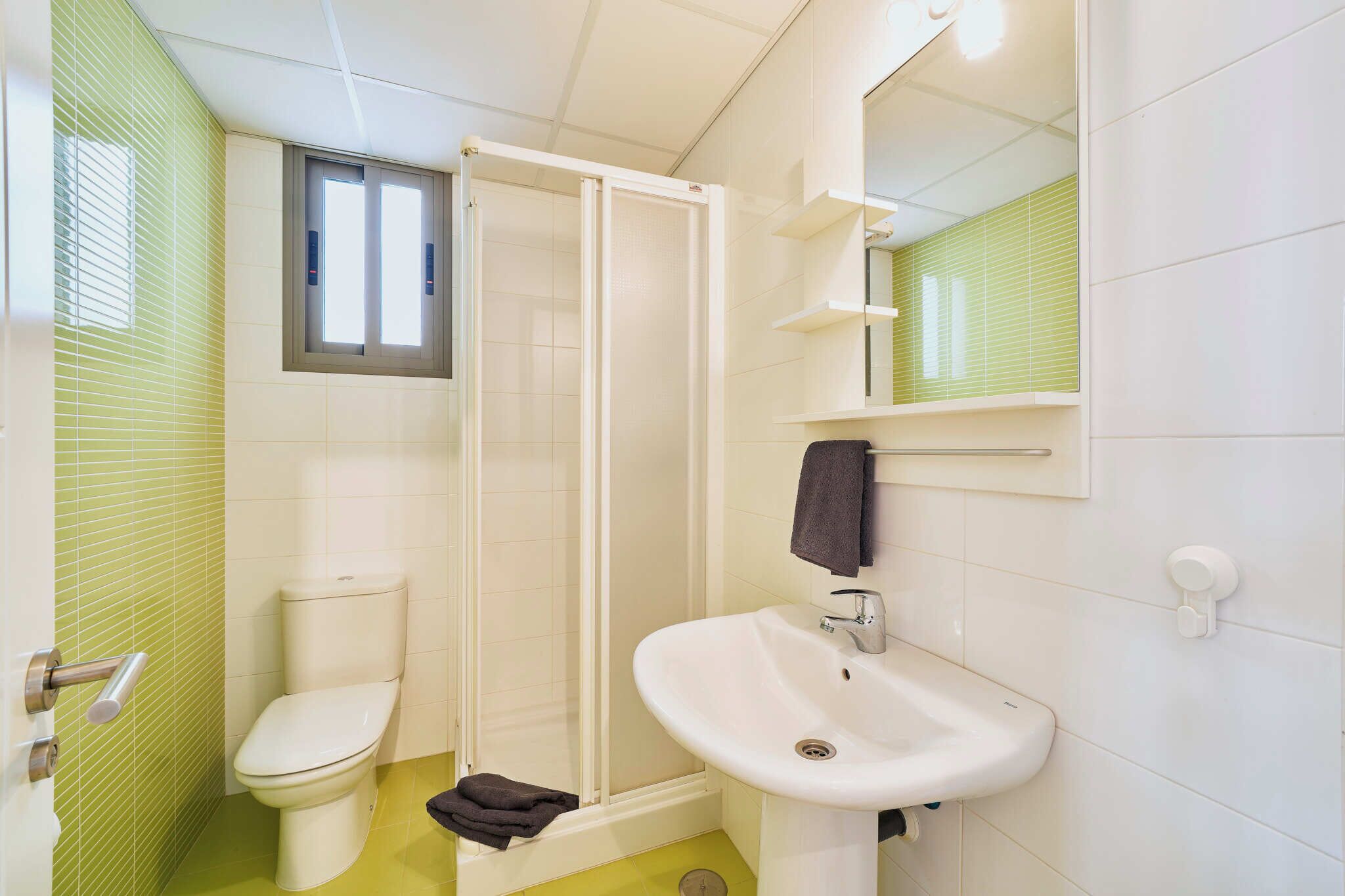 Ein Badezimmer mit Toilette, Dusche, Waschbecken und Spiegel.