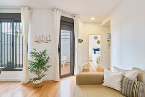 A modern living room with a sofa, a potted plant, and a sliding glass door leading to a balcony. - Solaga - Birgit (Málaga)