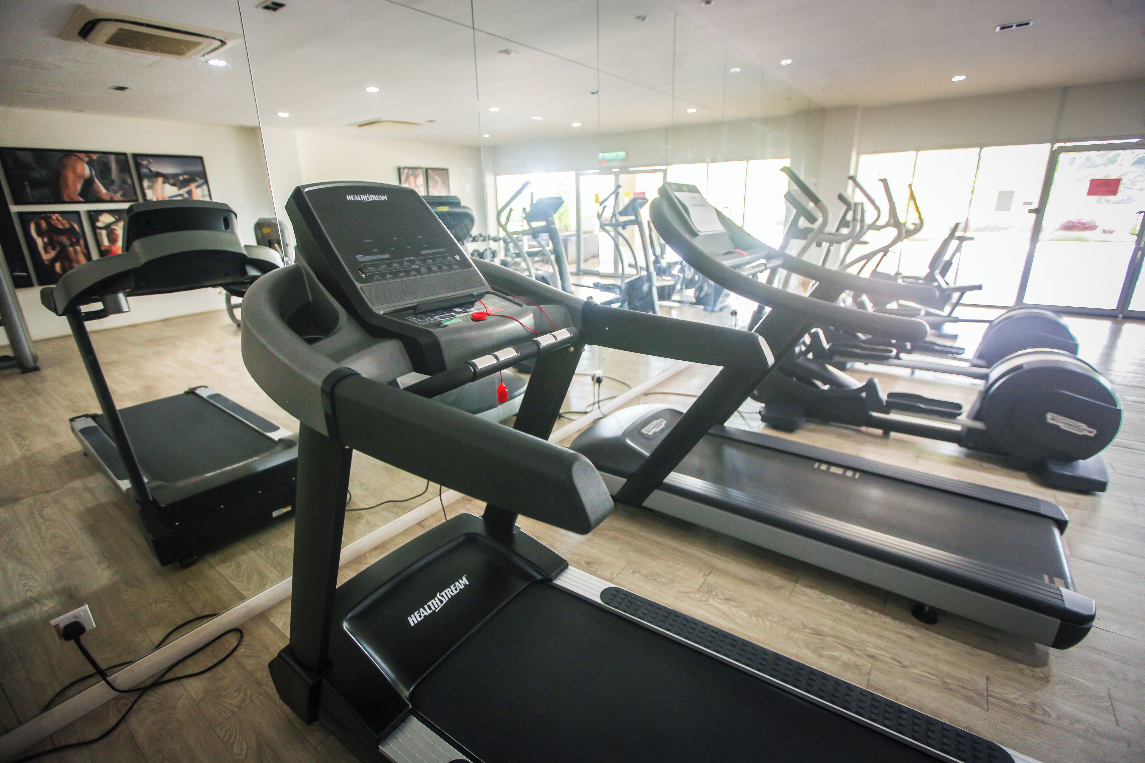 A gym with treadmills, elliptical machines, and a weight bench.
